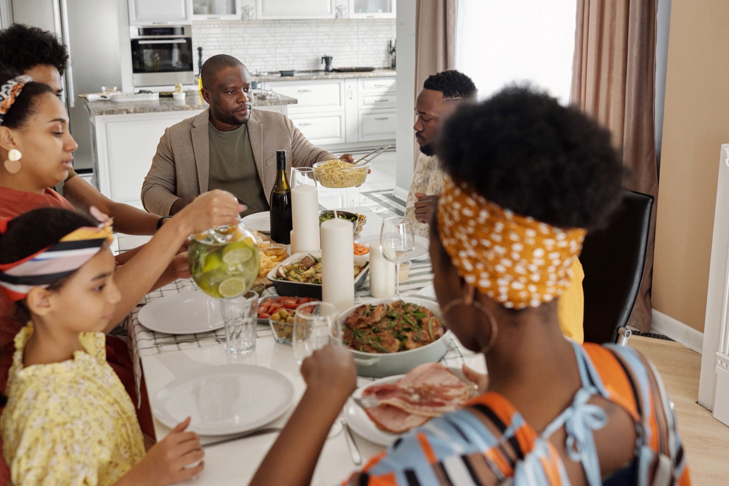 Uma família reunida com alegria a partilhar uma refeição em casa, celebrando a união e a convivência.