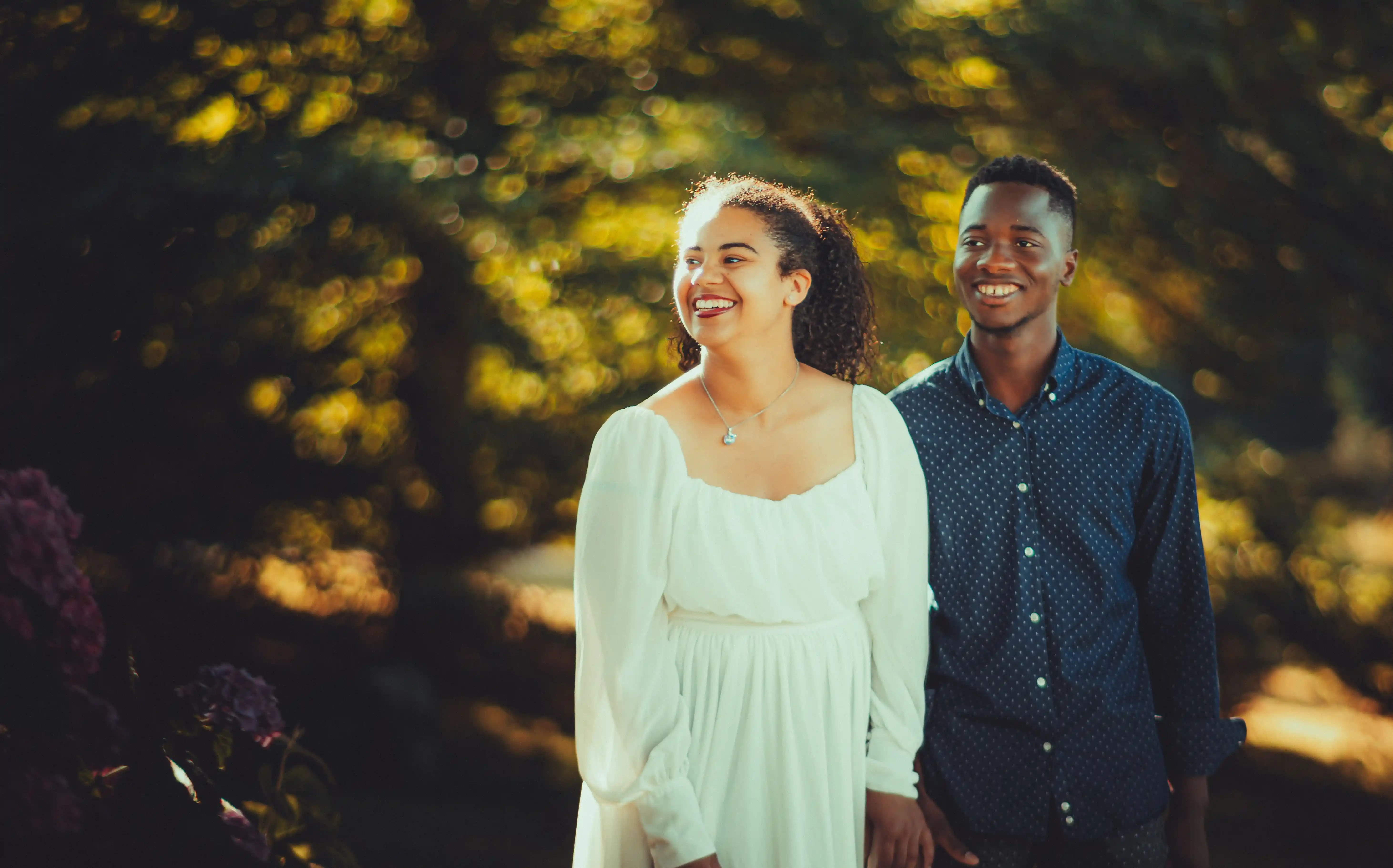 Um casal sorridente a passear junto num jardim iluminado pelo sol
