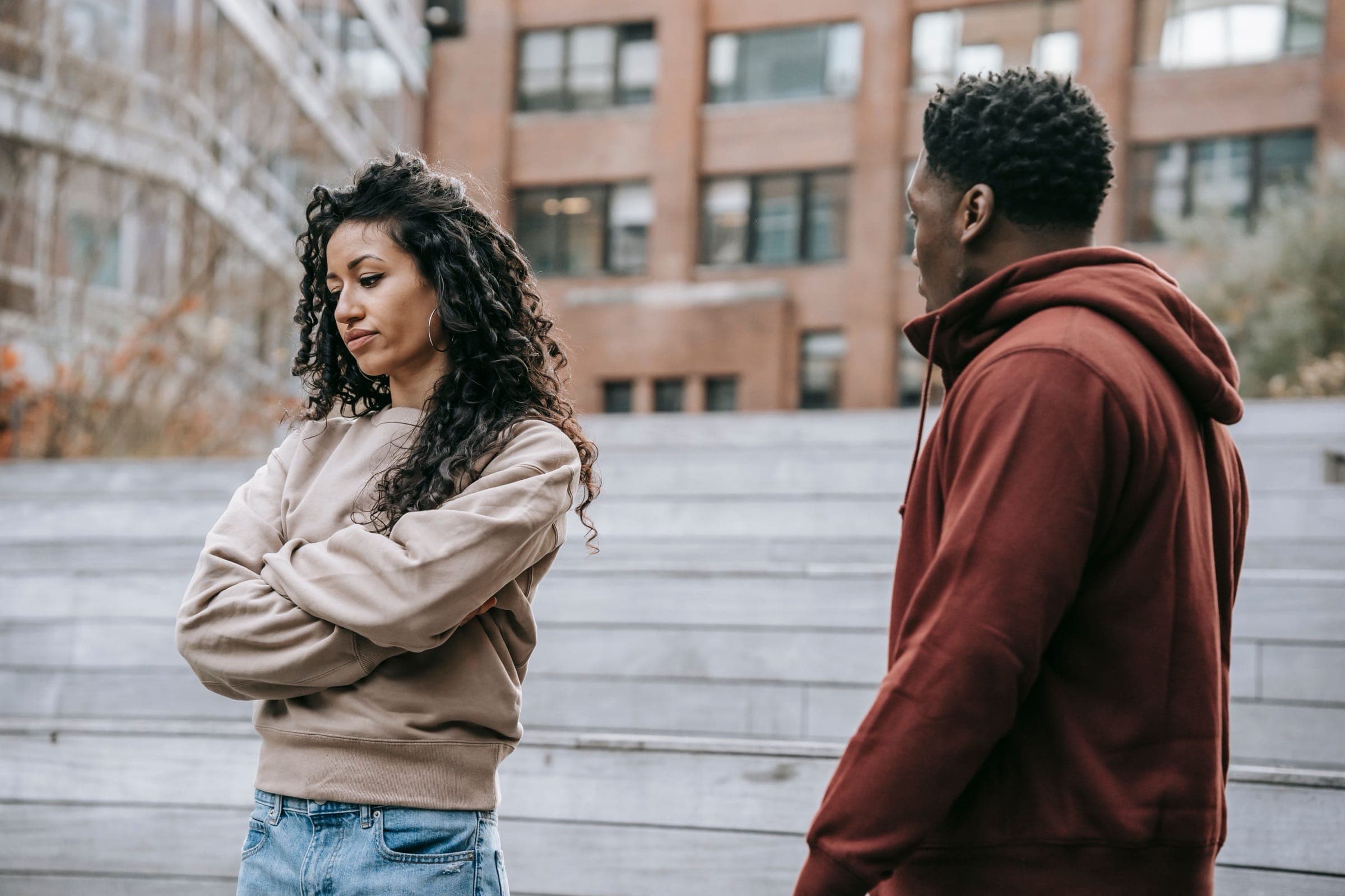 Um casal numa discussão acesa ao ar livre, mostrando frustração e descontentamento.